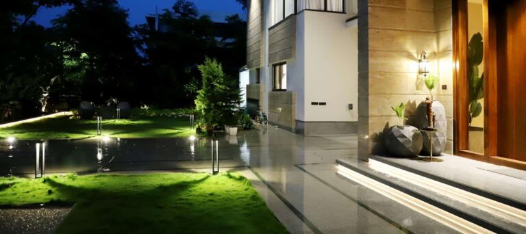 Elegant residential architecture illuminated at night, showcasing modern design and lush garden.